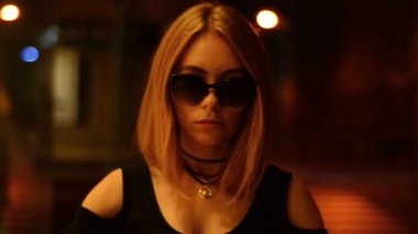 gözlük güzel Bayan kameraya bakar ve karanlık bir şehir gider