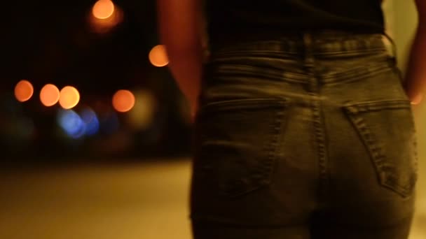 Chica con sexy nalgas en jeans va alrededor de la ciudad tarde en la noche — Vídeos de Stock