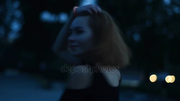 Felice ragazza sorridente guarda nella fotocamera e cammina a tarda notte per strada — Video Stock