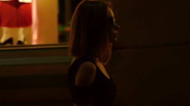 Красива леді в окулярах йде вночі на вулиці з серйозним обличчям — стокове відео