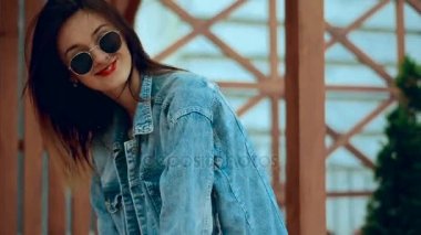 güzel sarışın genç güneş gözlüğü kırmızı dudaklar ile yürür ve kamera üzerinde gülümsüyor