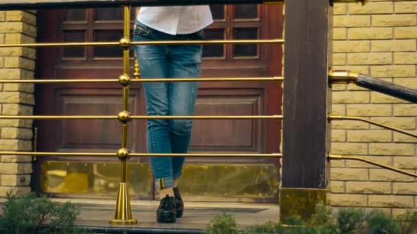 紧身牛仔裤的女人站在门廊上 — 图库视频影像
