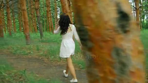 Joven morena en vestido blanco caminando en el bosque — Vídeo de stock