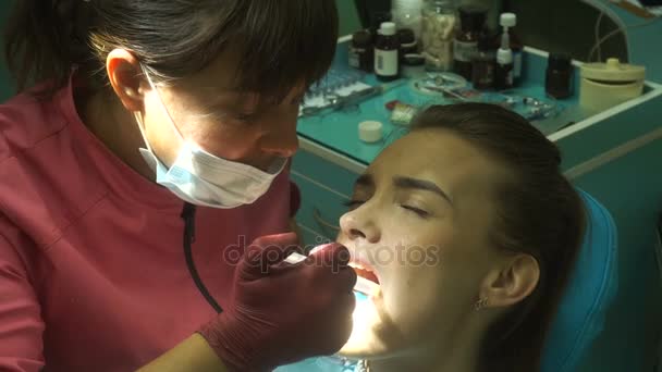 Bela mulher no dentista trata seus dentes — Vídeo de Stock