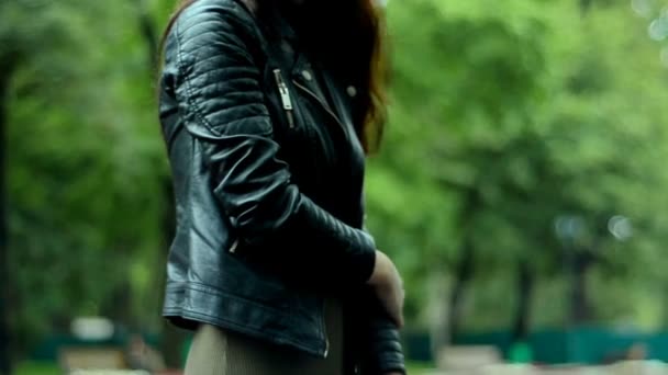 A young lady standing on the street in a black leather jacket — Stock Video