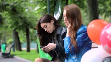 şirin kızlar cep telefonlarıyla parkta bir bankta oturmuş