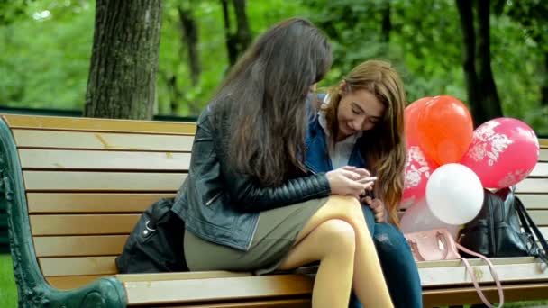 Cute girlfriends sit in autumn Park and watching a photo — Stock Video