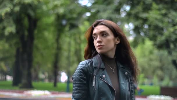 Остриженная девочка стоит на улице в черной куртке и смотрит вперед — стоковое видео