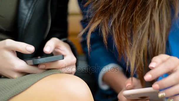 Chicas sentadas en un banco con teléfonos en las manos — Vídeo de stock