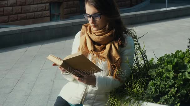 Mladá krásná bruneta žena v brýlích, čtení knihy — Stock video