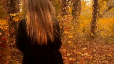 Altın sonbahar orman üzerinde siyah ceket neşeli kız yürüyor