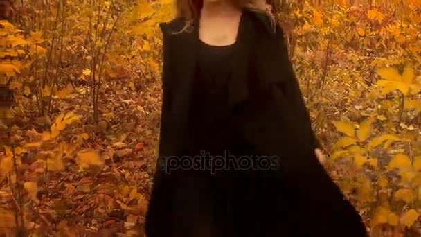 Jovem menina de casaco preto caminha na floresta dourada de outono — Vídeo de Stock