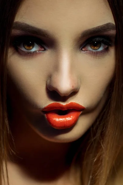 Close-up van portret van mooie jonge vrouw met bruine ogen en make-up bitting een lippen en kijken naar de camera — Stockfoto