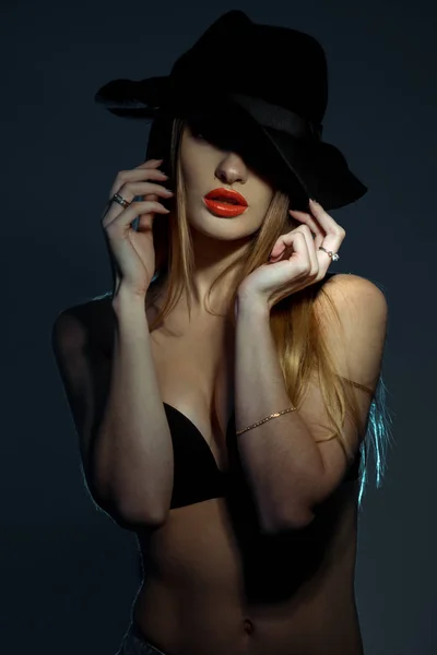스튜디오에서 넓은 테두리를 가진 모자를 쓰고 빨간 입술과 검은 브래지어에 슬림 젊은 여자의 초상화를 수직 — 스톡 사진