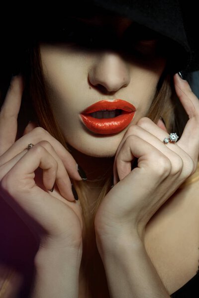 Close up portrait of girl with healthy skin and red lips with her eyes in shadow in studio