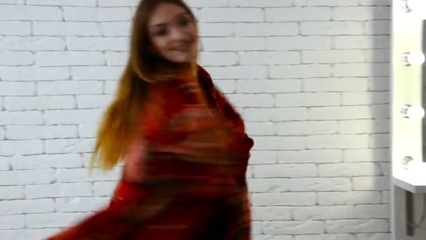 Bella ragazza felice si trova vicino alle pareti bianche coperte di coperta sorridente e ruota — Video Stock