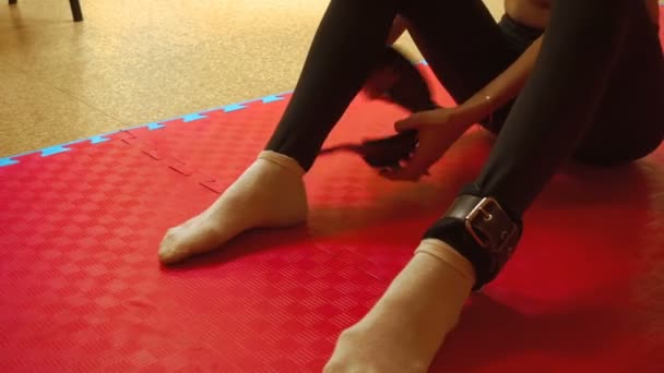 Flickan sätter på benmanschetterna sport i ett gym — Stockvideo