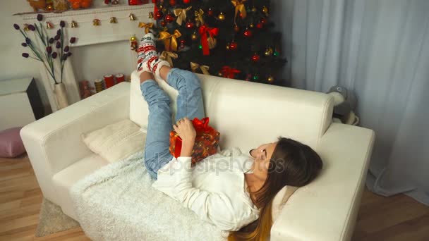 Chica acostada en un sofá y hablando por teléfono cerca de un árbol de Navidad — Vídeos de Stock