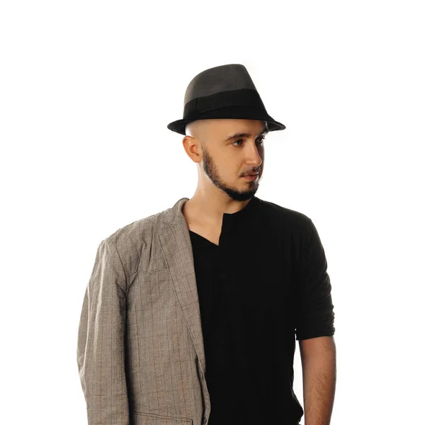 Serious young unshaved man in hat and jacket looking away — Stock Photo, Image