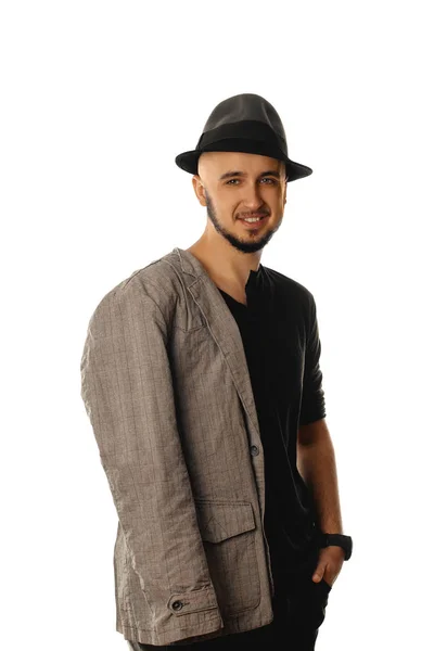 Gelukkig unshaved jongeman in hoed en jas glimlachend op camera — Stockfoto