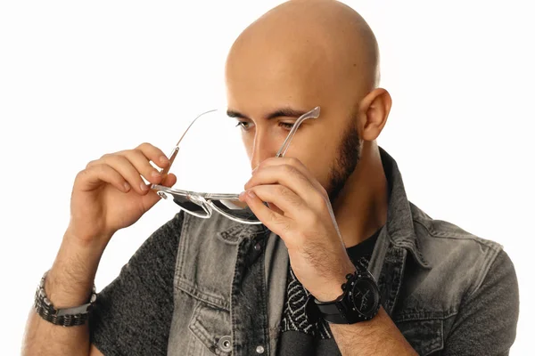 Joven hombre guapo con gafas de sol en las manos posando en el estudio —  Fotos de Stock