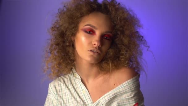 Krásná mladá dívka s nadýchanými kudrnaté vlasy a barevný make-up — Stock video