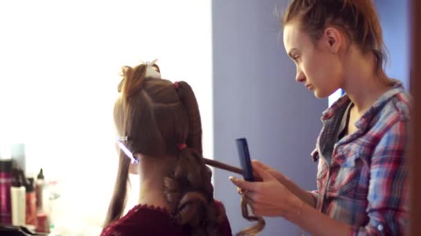 Blonde stylist girl makes hairstyle to a young woman — Stock Video