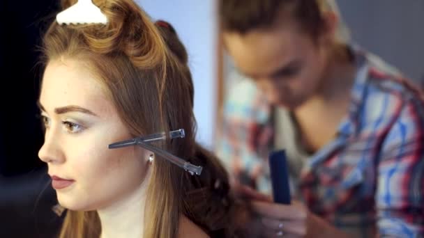 Blonde stylist girl makes hairstyle to a young woman — Stock Video