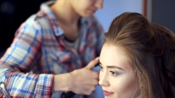 Blonde stylist girl makes hairstyle to a young woman — Stock Video