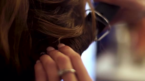 Blonde stylist girl makes hairstyle to a young woman — Stock Video