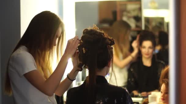 Young blonde stylist girl makes hairstyle to a woman — Stock Video