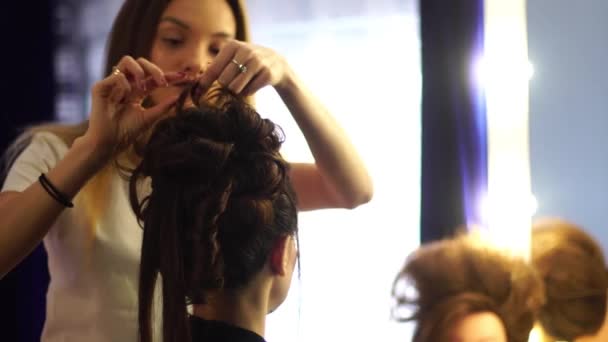 Fiatal szőke stylist lány teszi a frizura a nő — Stock videók
