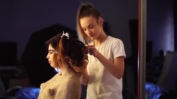 Young stylist girl makes hairstyle to a lady — Stock Video