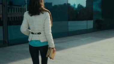 neşeli genç esmer öğrenci kız gülümser ve el kitaplarında ile sokakta yürüyor