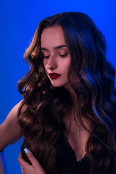 Niedliches Mädchen mit lockiger Frisur auf blauem Hintergrund — Stockfoto