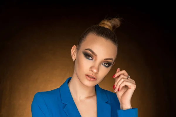 Hermosa joven en chaqueta azul con maquillaje de belleza en el estudio — Foto de Stock