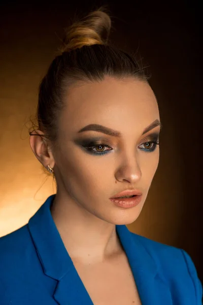 Smuk ung pige i blå jakke med skønhed makeup i studiet - Stock-foto