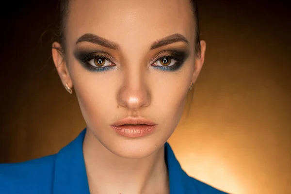 Hermosa joven en chaqueta azul con maquillaje de belleza en el estudio — Foto de Stock