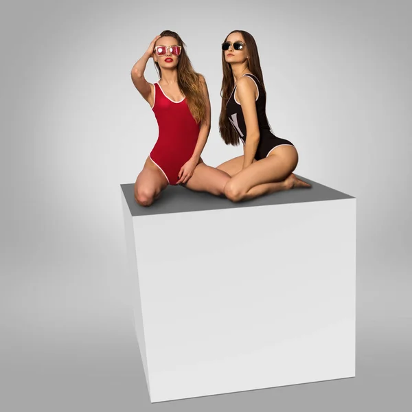 Δύο πανέμορφα κορίτσια που κάθεται σε ένα κύβο στο studio — Φωτογραφία Αρχείου