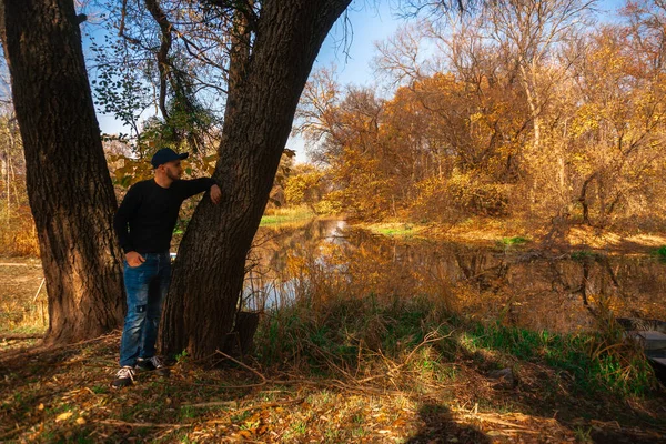 Красивий хлопець стоїть на березі річки восени — стокове фото