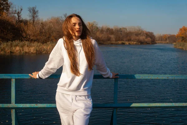 Hermosa chica en ropa blanca se para en el puente — Foto de Stock