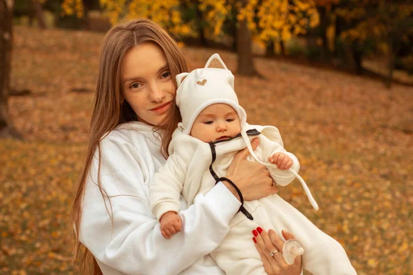 beautiful young mom with baby in autumn