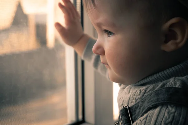 Милая маленькая девочка, выглядывающая в окно — стоковое фото