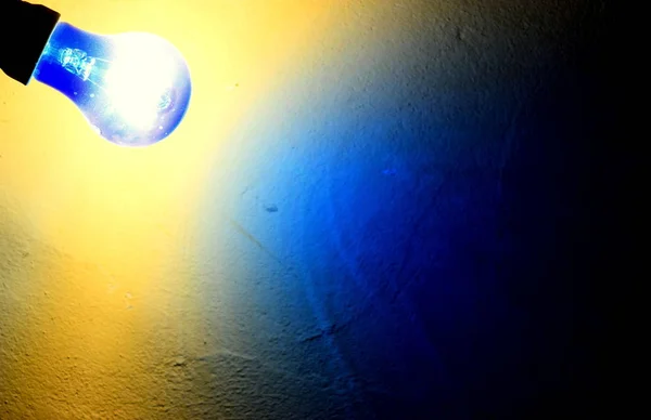 Sarı bir duvarda mavi bir ampul parlıyor.