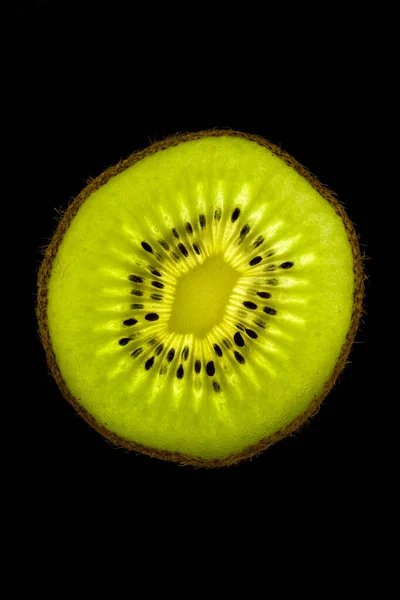 Kiwi slice backlited in a black background — Stock Photo, Image