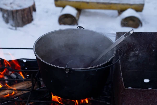 Op een vuur in een pot om glühwein te bereiden. Warme rode wijn op een open vuur in de winter. — Stockfoto