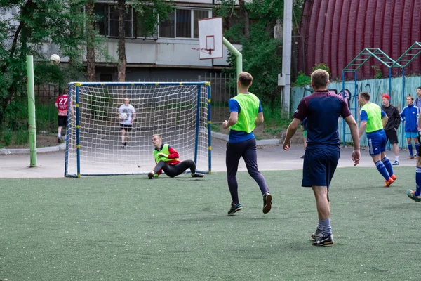 Rusia, Jabárovsk - 11 de junio de 2019: local callejero jugando fútbol. Chicos jóvenes juegan al fútbol en una hierba verde —  Fotos de Stock