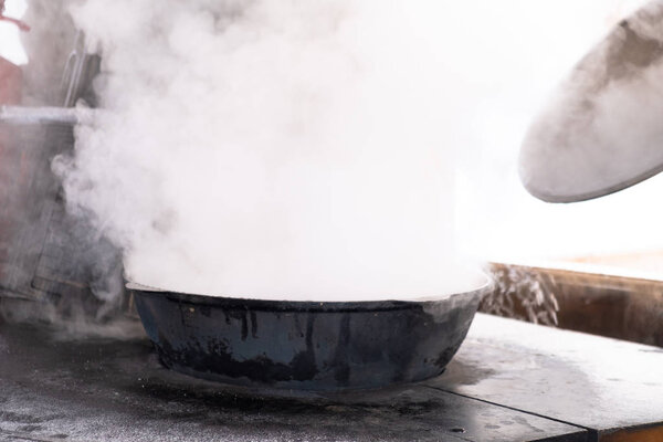 Preparation of shurpa in a cauldron on a Russian stove on an open fire.