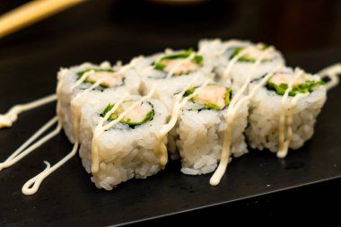 Real Japanese sushi in a restaurant in Tokyo. Set of sushi on a black plate made of stone.