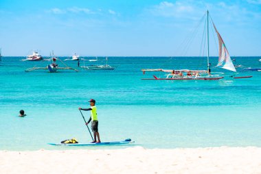 Boracay, Filipinler - 20 Ocak 2020: Gündüz vakti Boracay adasının boş beyaz plajı. Koronavirüs yüzünden Çinli turist yok. Denizdeki tekneler turist taşır..